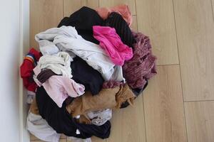 Laundry pile mixed with clean and dirty clothes on floor photo