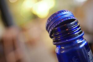 Blue bottle with a silver cap resting on a table photo