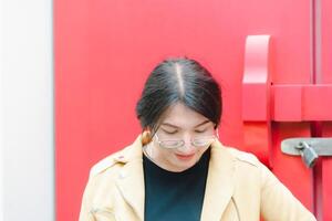 A woman in glasses standing in front of a red door photo