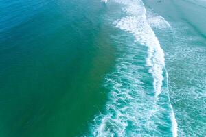 overhead perspective of a tranquil ocean with a single breaking wave and subtle human presence photo