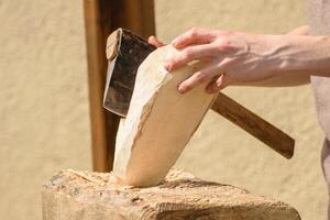 a craftsman works on a piece of wood with a small axe shaping wood with traditional tools photo