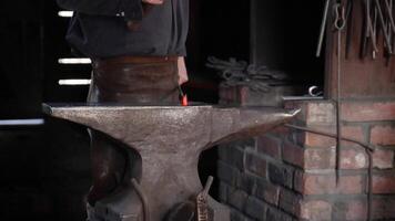 Blacksmith hammering metal at anvil in workshop video
