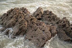 a large rock formation in the ocean with waves photo