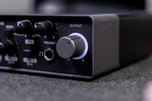 Close-up of a black audio interface showing output and phones controls, crucial equipment for professional music production and home studio recording setups photo