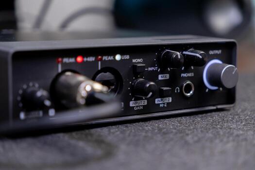 Compact black audio interface with various control knobs, input ports, and text labels like PHONES and OUTPUT, essential for home studio music production setups photo