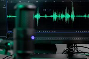 Professional desktop microphone with vibrant green audio waveform on monitor, illustrating sound engineering, podcasting, and digital content creation photo