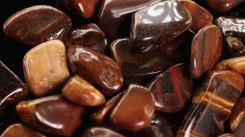 A detailed view of polished tiger's eye stones with rich brown hues and glossy surfaces, captured in warm lighting video