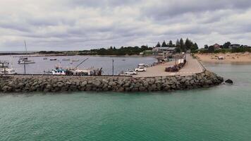 Drone footage captures Apollo Bay's harbor, showcasing boats, jetty, and rock wall under overcast skies video
