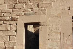 Ancient egyptian stone wall with carvings and open doorway. Egyptian drawings on the wall of Karnak temple in Luxor, Egypt. photo