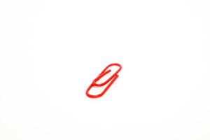 A vibrant red paper clip isolated against a clean white background, highlighting simplicity and office essentials photo