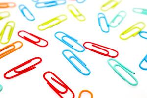 Colorful Paper Clips Scattered on a White Surface Creating a Playful Pattern photo