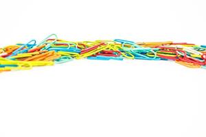 A vibrant pile of colorful paper clips scattered on a clean white background, perfect for office supplies or organization concepts photo