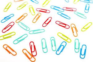 Vibrant Array of Colorful Paper Clips Scattered on a Clean White Surface Creating a Dynamic Composition photo
