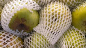 Close-up of Green Apples in Protective Netting at a Supermarket, Ready for Purchase photo