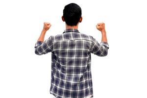 Rear view of a celebrating Asian man in a plaid shirt with fists raised in success on a white background photo