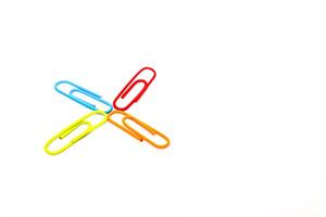 Colorful paper clips arranged in a radial pattern on a clean white background, minimal style photo