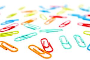 Scattered colorful paper clips on a white surface creating a vibrant pattern and a sense of disorganization or creativity photo