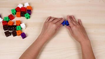 Hands assembling cubes on a wooden table video