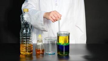 A scientist conducts a colorful liquid experiment, creating a lava lamp effect using various liquids and a stirring rod video