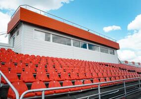a top section of a stadium with plastic seats. Commentator's box at the stadium. Ideal for use in articles about sports venues, event planning, or urban infrastructure. photo