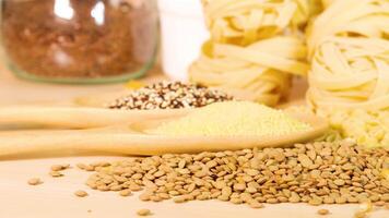Close-up of various grains and pasta on a wooden surface with soft lighting, highlighting texture and color contrast video