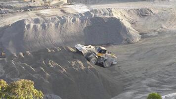 Aerial footage of a loader moving sand in a Gold Coast quarry. Bright daylight highlights the machinery and terrain video
