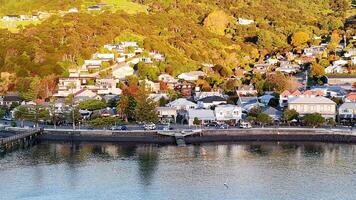 Drone footage captures Akaroa's scenic waterfront and hillside homes during golden hour, highlighting vibrant colors and tranquil waters video