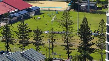Drone footage captures a lively soccer match on a sunny day at Broadbeach, showcasing vibrant green fields and surrounding buildings video