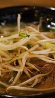 Close-up shots of a steaming bowl of Vietnamese pho, highlighting noodles, beef, and bean sprouts under warm lighting video