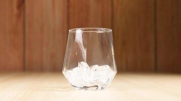 Ice cubes falling into an empty glass video