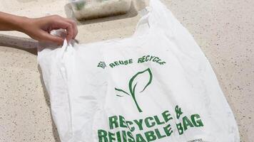 Hands interact with a recyclable bag on a kitchen countertop. Bright lighting highlights the bag's eco-friendly message video