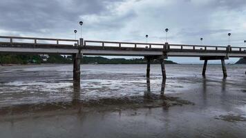 A drone captures a tranquil scene of a pier in Phuket, Thailand, with overcast skies and calm waters, highlighting the natural beauty video