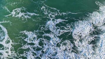 Drone captures dynamic ocean waves with frothy patterns and vibrant turquoise hues under bright daylight video