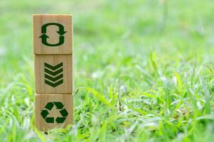 Wooden cube stack with recycle, reuse, reduce icons on green grass. Environmental concept. photo