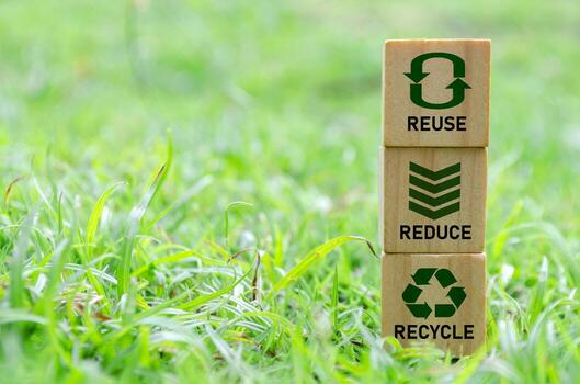 Wooden cube stack with text that reads recycle, reuse and reduce icons on green grass. Environmental concept. photo