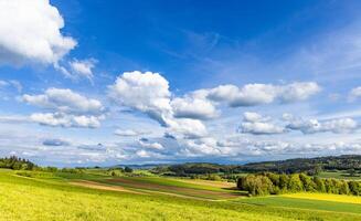 Valley with meadows, fields, forest and farms against a cloudy sky photo