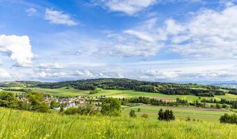 View of a forest, fields and village on the hills against a clouForest fields village on hills against cloud photo