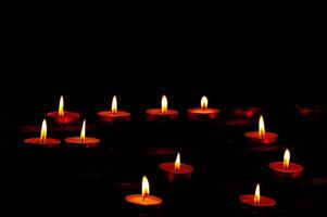 Illuminated red tealight candles against dark background photo