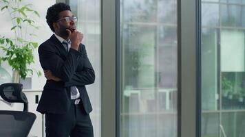 Thinking problem solution African American business man looking window in office decide trouble work job failure tired businessman hard difficult decision leaning on glass think male hesitate puzzled video
