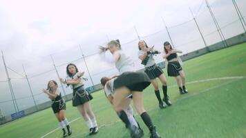 A dynamic dance performance on a sports field, featuring multiple dancers in stylish outfits. The scene captures energy and movement, with a focus on one dancer in the foreground. video
