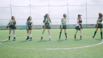 A group of six dancers performing on a green soccer field, wearing stylish outfits. They are in motion, showcasing choreography with energetic expressions video