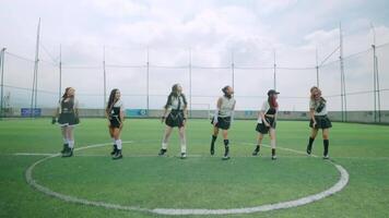 A dynamic dance performance on a soccer field, featuring four dancers in stylish outfits. The scene captures movement and energy under a cloudy sky. video