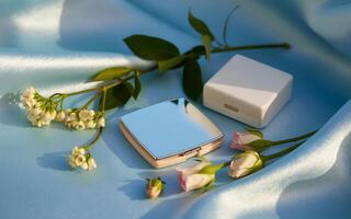 A compact mirror and a flower on a blue satin photo
