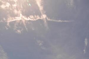 Sun-kissed sky streaked with ethereal clouds and lingering contrails, painting a dynamic atmospheric canvas. photo