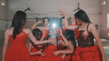 A group of dancers in red dresses performing in an industrial space. Their movements create a dynamic and energetic atmosphere, with flowing hair and vibrant attire. video