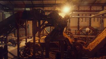 A detailed view of an industrial machine in a factory setting, showcasing gears, belts, and a warm glow from overhead lights. The environment is filled with machinery and a sense of activity. video