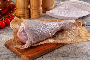 Raw chicken on a cutting board with a knife and a tomato photo