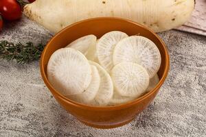A bowl of sliced white radishes sitting on a table photo
