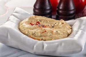 A bowl of hummus with a bottle of red wine photo