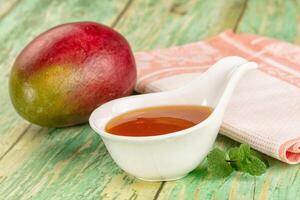 A spoon with a mango and a spoon of syrup photo